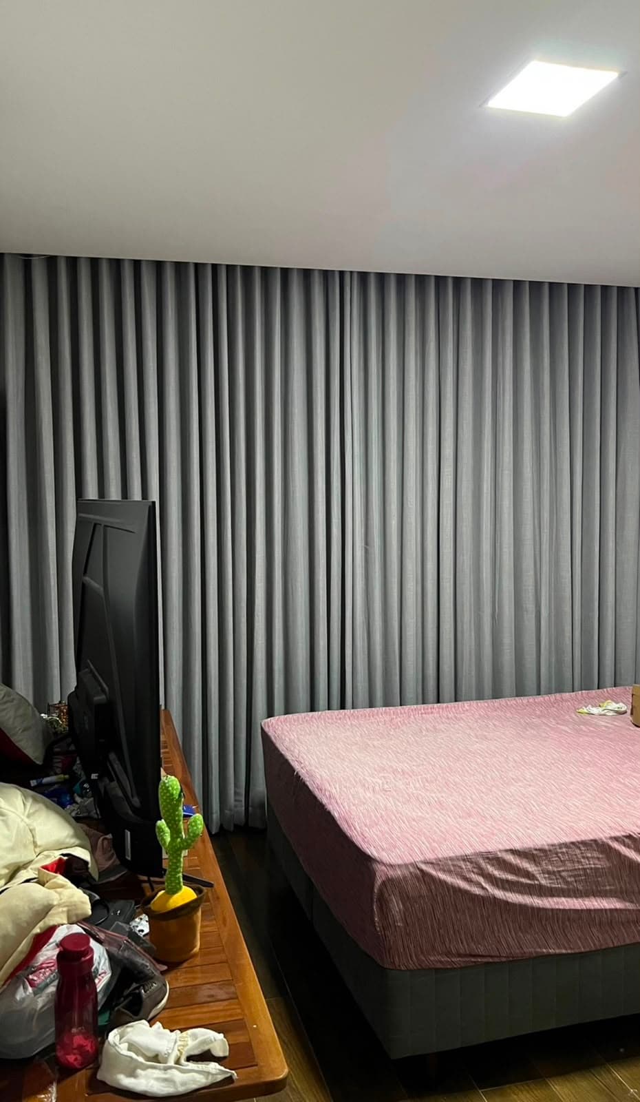 Quarto de casal com cortina blackout cinza cobrindo a parede inteira atrás da cama