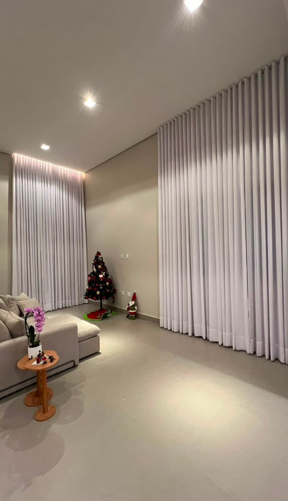 Sala ampla e iluminada com cortinas brancas wave em duas janelas altas