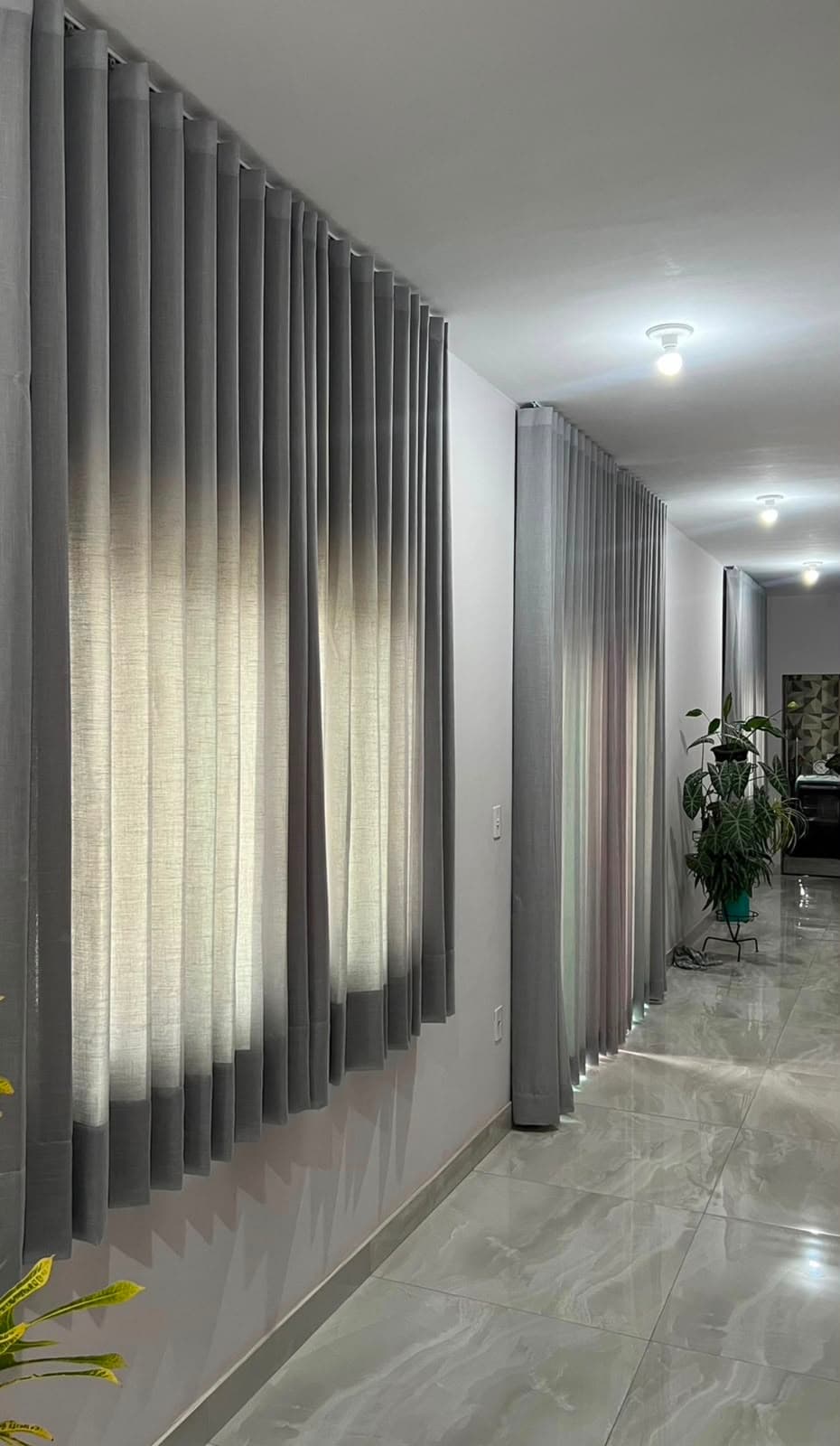Corredor de piso de mármore com cortinas cinza claras ao longo das janelas
