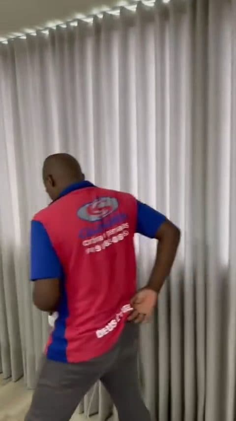 Vídeo aproximado de uma cortina clara recém-instalada, mostrando o caimento das pregas do teto ao chão